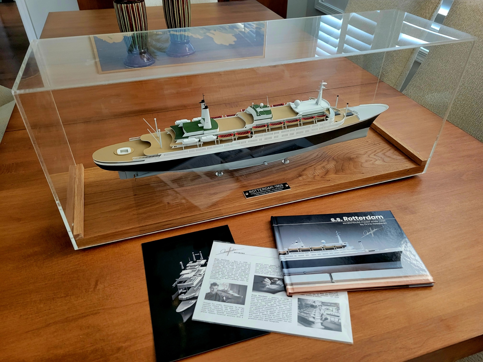 SS Rotterdam V scale model displayed with its plexiglass cover, accompanied by a booklet on its creation